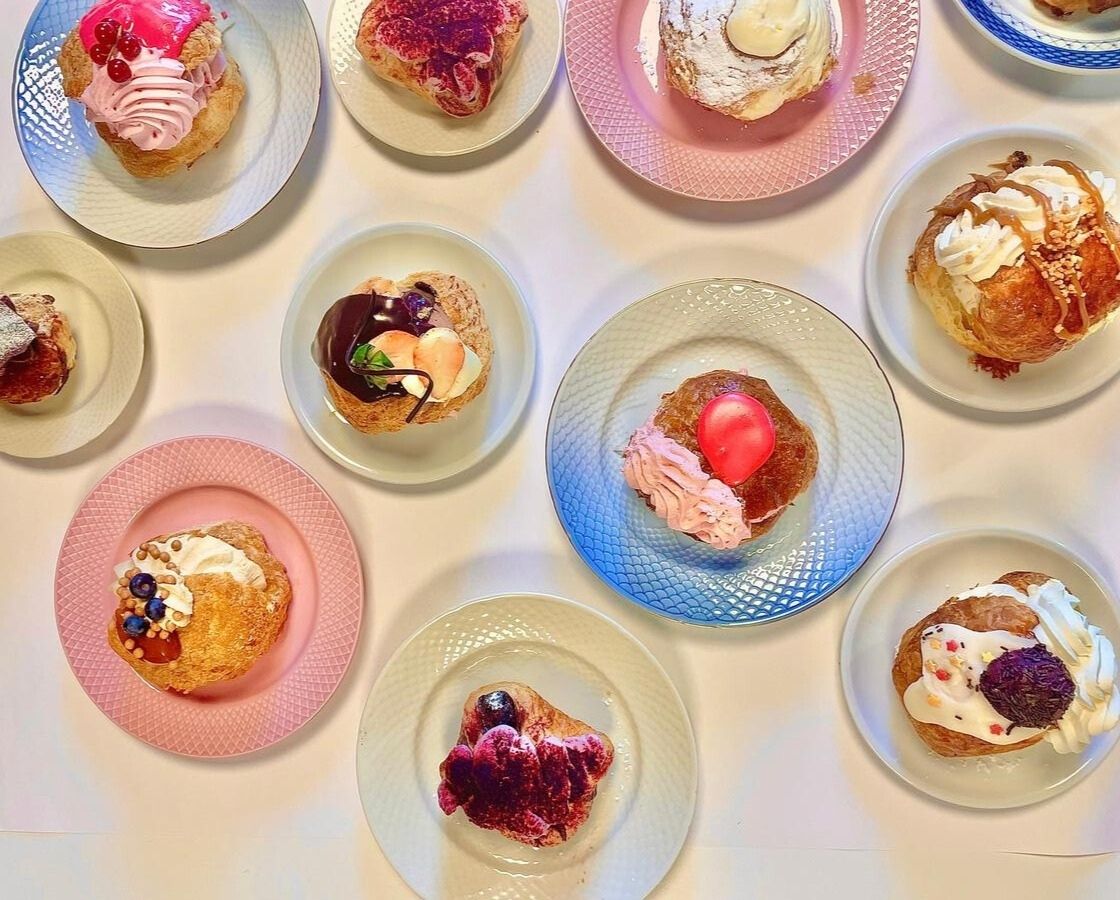 Flere farverige fastelavnsboller arrangeret på forskellige tallerkener set ovenfra.