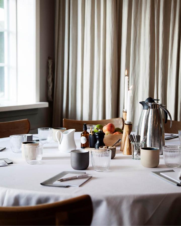Opdækket mødebord i Herthadalen med kaffekande, glas, keramikkrus, frugtskål og blokke til notater.
