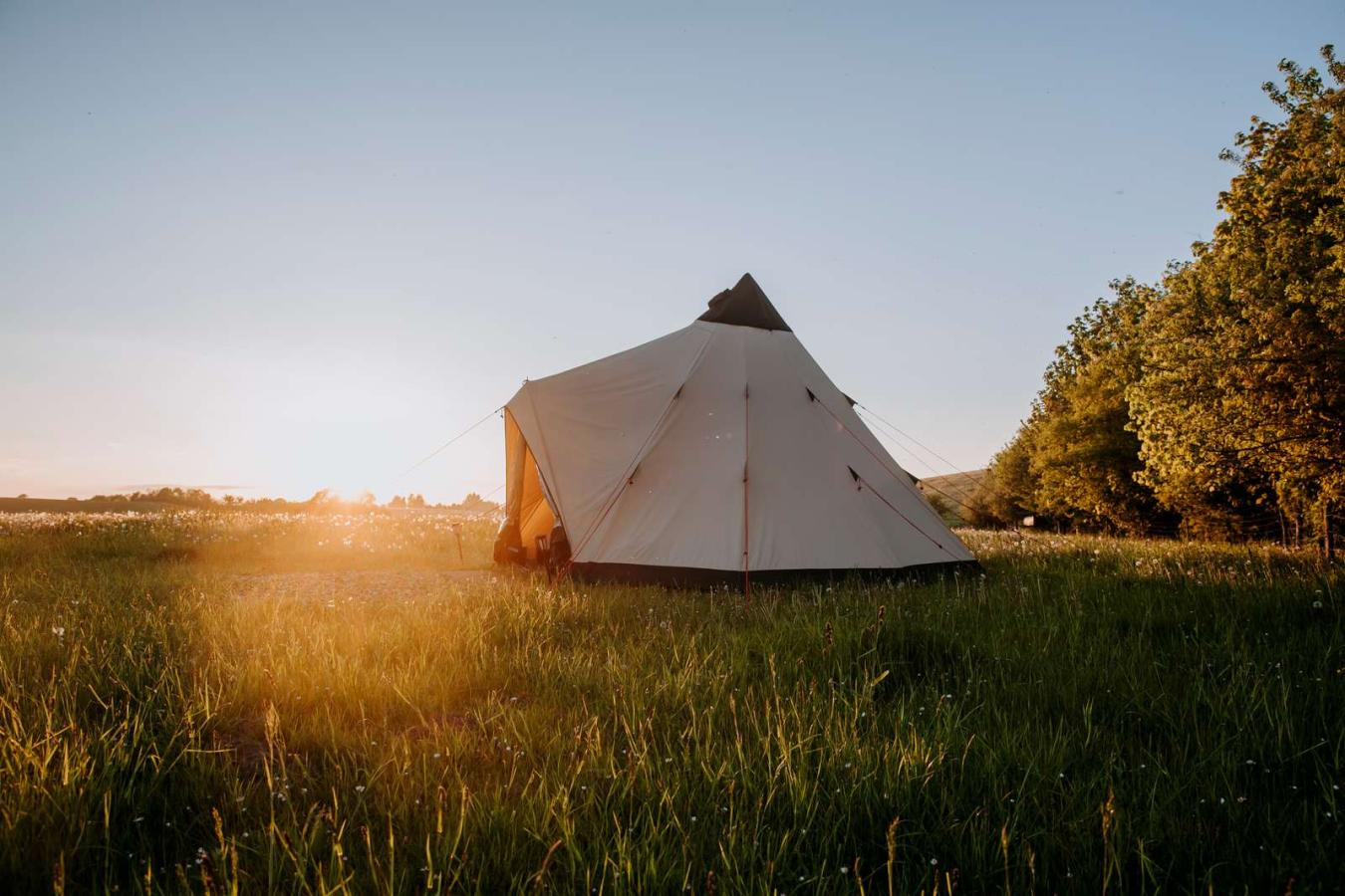 Glampingtelt opsat i åbent landskab ved solnedgang hos Outdoor Adventures.